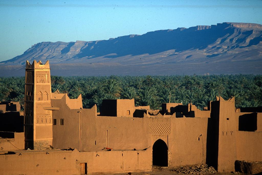 Straße der Kasbah vor einer Oase und einer Bergkette