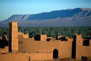 Kasbah vor einer Oase und einer Bergkette