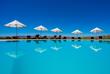 Zu sehen ist der Pool der GocheGanas Lodge mit weißen Sonnenschirmen.