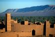 Straße der Kasbah vor einer Oase und einer Bergkette