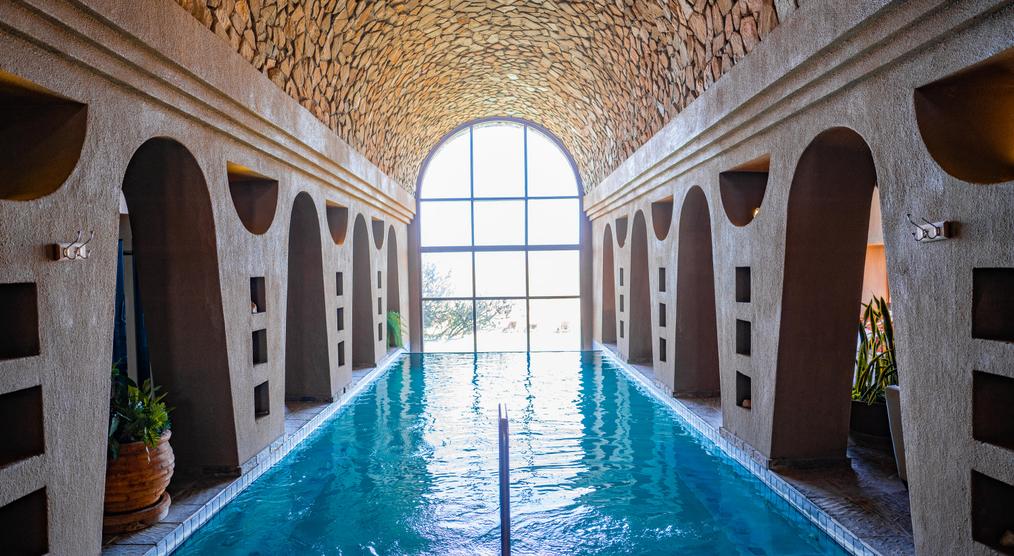 Wellnessanlage mit Pool, umgeben von hohen Steinwänden und einer beruhigenden Atmosphäre, perfekt zum Entspannen.