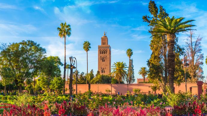 Blick auf die Koutoubia Moschee in Marrakesch, umrandet von Palmen und Blumen