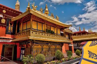 Blick ins Innere des Jokhang-Klosters in Lhasa, Tibet, mit buddhistischen Statuen, Gebetsfahnen und tibetischer religiöser Kunst, umgeben von Pilgern und Gläubigen.
