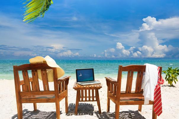 Strand mit Stühlen und Laptop