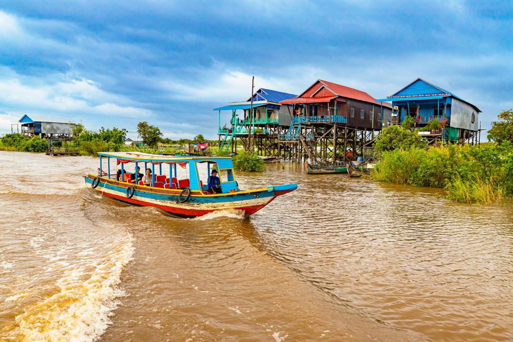 Ein Boot vor schwimmenden Holzhäusern auf dem Tonle Sap See