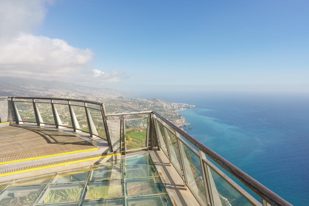 Zu sehen ist die Aussicht von der Cabo Girão Klippe bei Funchal – steile Felsen fallen dramatisch zum Atlantik ab, im Vordergrund eine Glasplattform.
