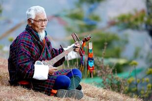 Bhutaner spielt auf traditionellem Musikinstrument