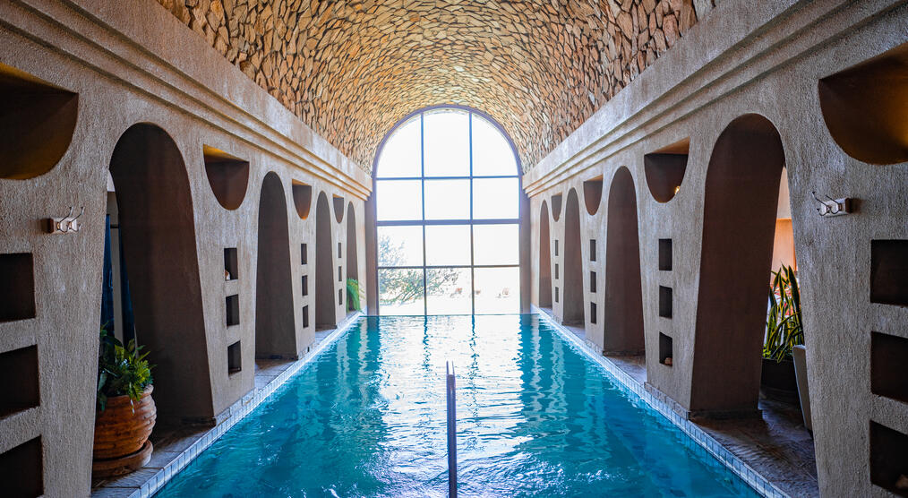 Wellnessanlage mit Pool, umgeben von hohen Steinwänden und einer beruhigenden Atmosphäre, perfekt zum Entspannen.