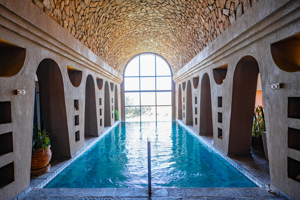 Wellnessanlage mit Pool, umgeben von hohen Steinwänden und einer beruhigenden Atmosphäre, perfekt zum Entspannen.