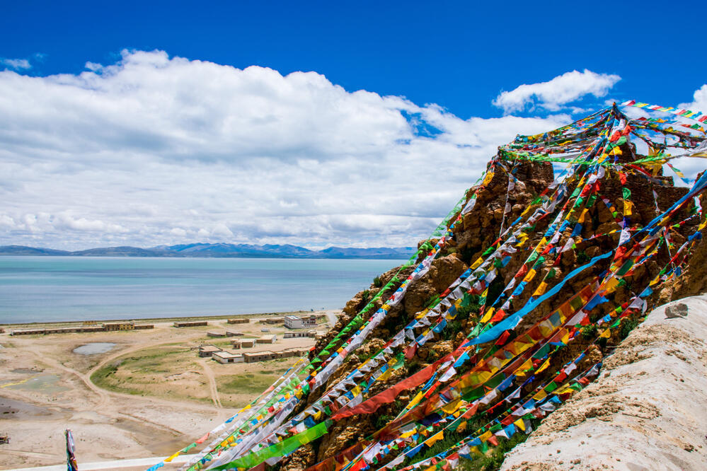 Der heilige Manasarovar-See in Tibet, umgeben von majestätischen Bergen, dessen kristallklaren, transparenten blauen Wasser die beeindruckende Berglandschaft widerspiegelt. 