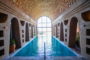 Wellnessanlage mit Pool, umgeben von hohen Steinwänden und einer beruhigenden Atmosphäre, perfekt zum Entspannen.