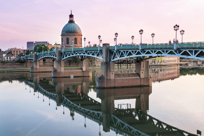 Die Saint-Pierre-Bruecke spiegelt sich im Fluss Garonne und im Dome de la Grave bei Sonnenuntergang in Toulouse