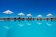 Zu sehen ist der Pool der GocheGanas Lodge mit weißen Sonnenschirmen.