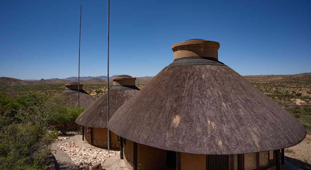 Zu sehen sind die Lodges von oben, eingebettet in eine weite Landschaft unter strahlend blauem Himmel.