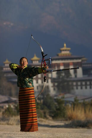 Bhutanische Frau beim traditionellen Bogenschießen
