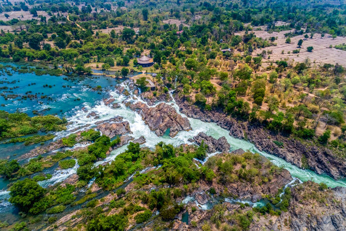 Zu sehen ist der Li Phi Wasserfall in Laos aus der Vogelperspektive, mit seinen beeindruckenden Wasserströmen, die sich über Felsen stürzen. 