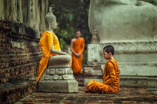 Meditierender Mönch vor Buddha Statue