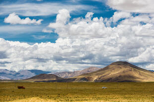Das Shigatse-Plateau in Tibet mit weiten Graslandschaften, die sich unter den majestätischen Gebirgsketten erstrecken. 