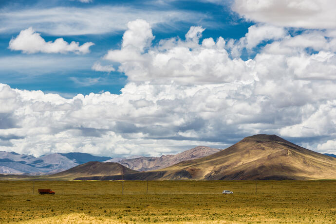 Das Shigatse-Plateau in Tibet mit weiten Graslandschaften, die sich unter den majestätischen Gebirgsketten erstrecken. 