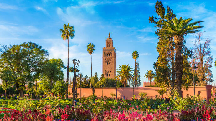 Blick auf die Koutoubia Moschee in Marrakesch, umrandet von Palmen und Blumen