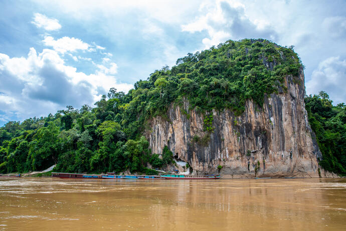 Zu sehen ist der Felsvorsprung der Pak Ou-Höhlen. Diese liegen malerisch am Mekong-Fluss und sind von steilen Kalksteinfelsen umgeben. 