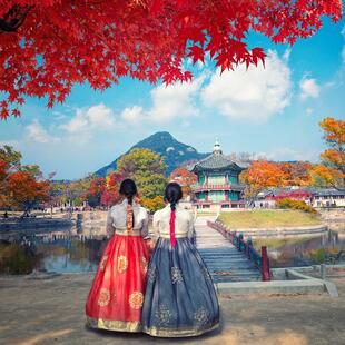 Zwei Koreanerinnen in traditioneller Kleidung mit Tempel im Hintergrund