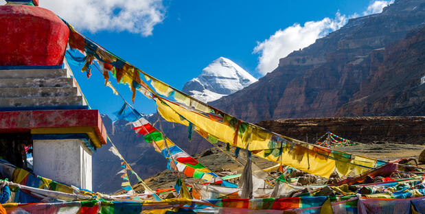 Farbenfrohe Gebetsfahnen wehen im Wind, mit dem heiligen Berg Kailash im Hintergrund. 