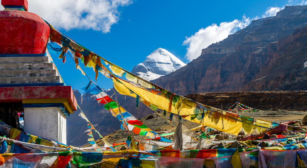 Farbenfrohe Gebetsfahnen wehen im Wind, mit dem heiligen Berg Kailash im Hintergrund. 