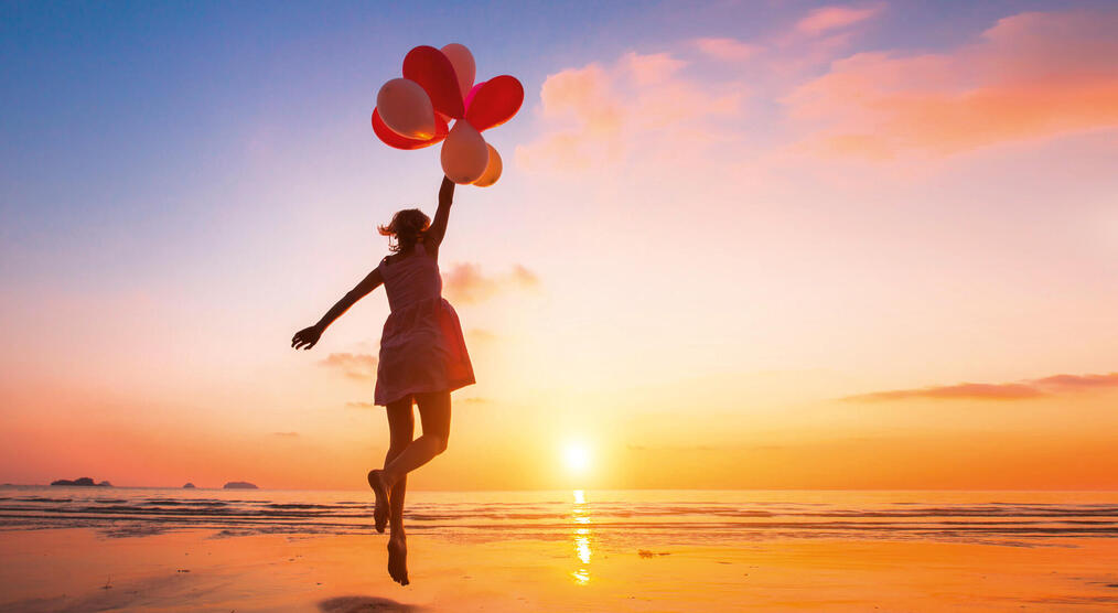 Frau mit Luftballons am Strand