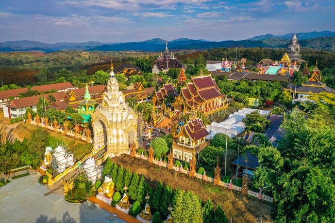 Zu sehen ist der Wat Saeng Kaeo Phothiyan Tempel in Chiang Rai, ein friedlicher Ort, der von kunstvoll gestalteten Gebäuden und bunten Verzierungen geprägt ist.