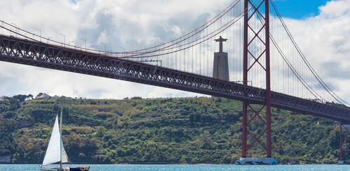 Ponte 25 de Abril und Cristo Rei mit Segelboot in Lissabon