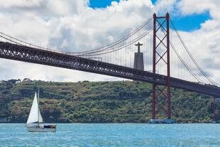 Ponte 25 de Abril und Cristo Rei mit Segelboot in Lissabon
